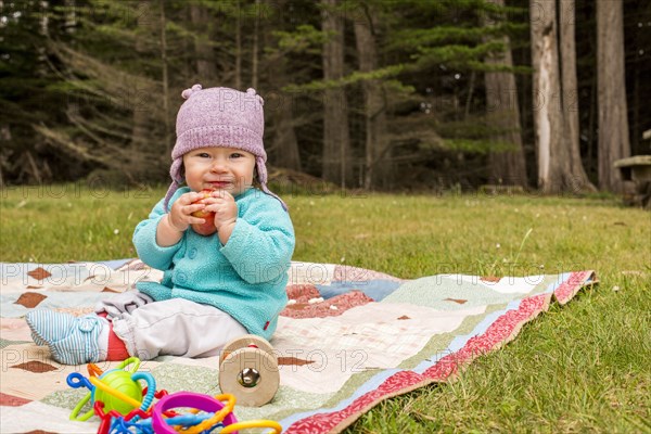 Caucasian baby girl sitting on blanket in grass