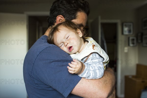Caucasian father holding sleeping baby girl