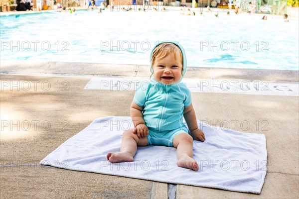 Caucasian baby girl sitting near swimming pool