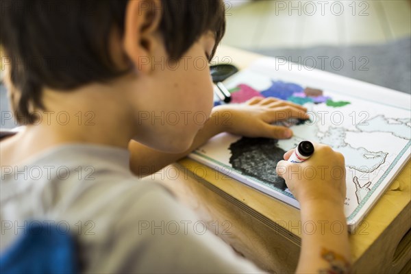 Mixed race boy coloring map with crayon