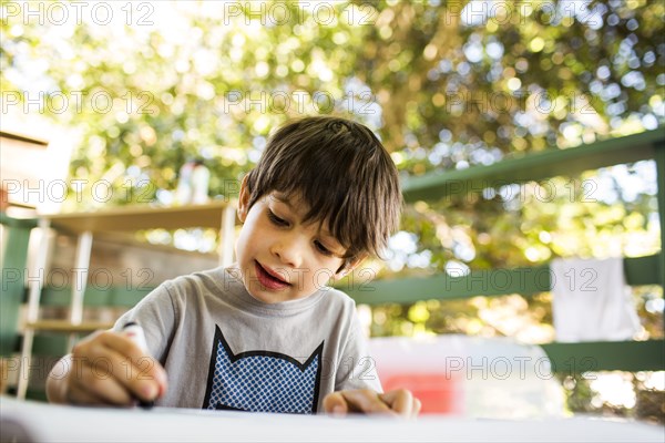 Mixed race boy coloring on porch