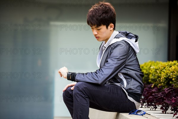 Asian man checking wristwatch in city