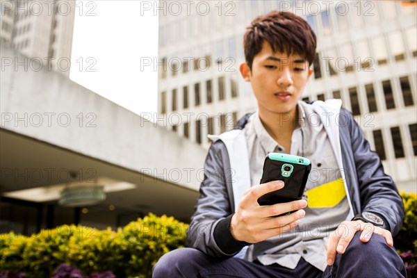 Asian man using cell phone in city