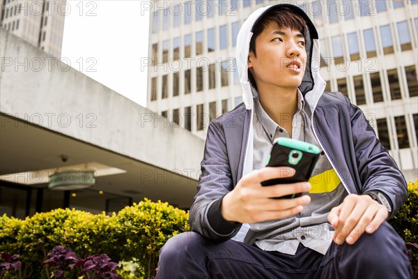 Asian man using cell phone in city