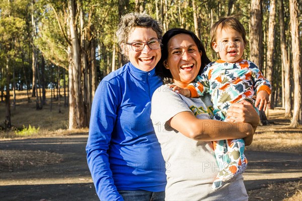 Lesbian couple holding baby in park