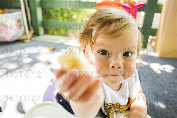 Caucasian baby girl eating on patio