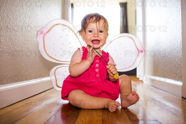 Caucasian baby girl playing in fairy wings