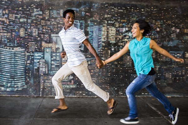 Couple running by mural on city sidewalk