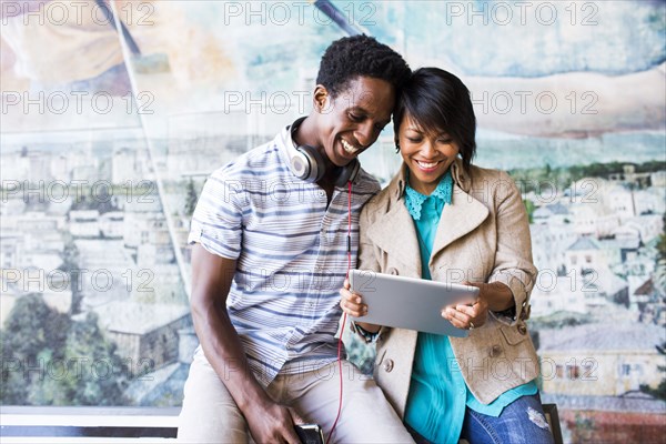 Couple sharing digital tablet by mural