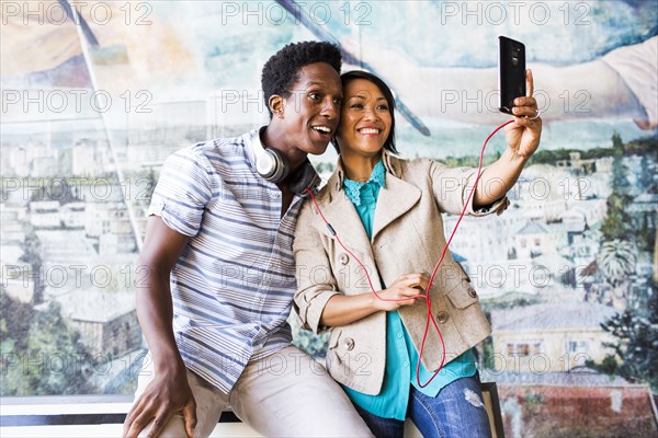 Couple taking selfie with digital tablet by mural