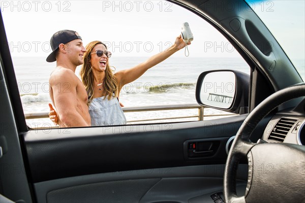 Caucasian couple taking selfie at beach