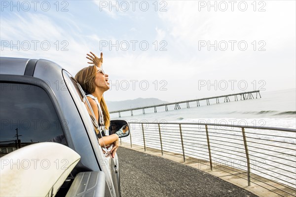 Caucasian woman leaning out car window at beach