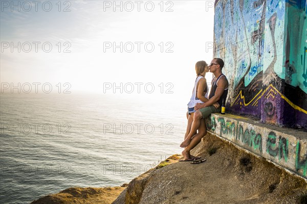 Caucasian couple kissing at mural on cliff
