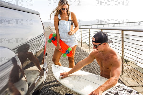 Caucasian couple waxing surfboard