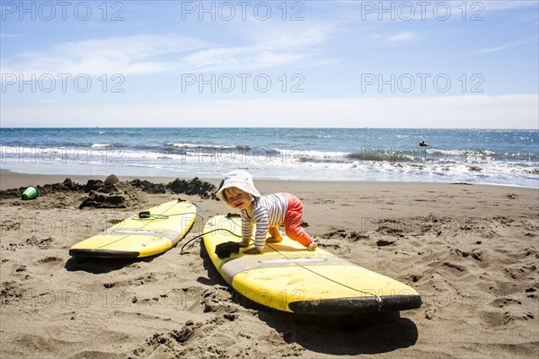 Caucasian baby crawling on surfboard
