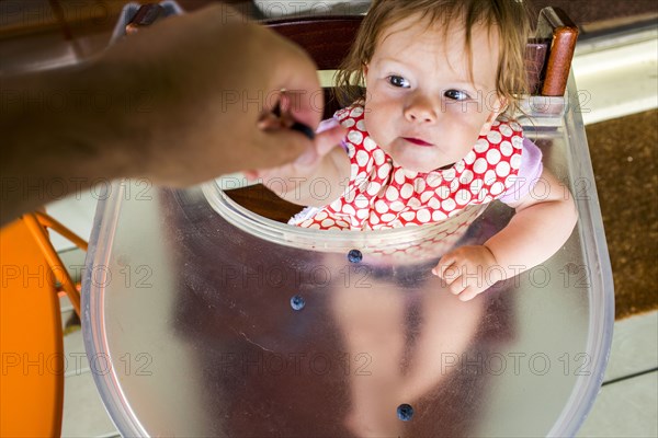 Father feeding baby girl in high chair