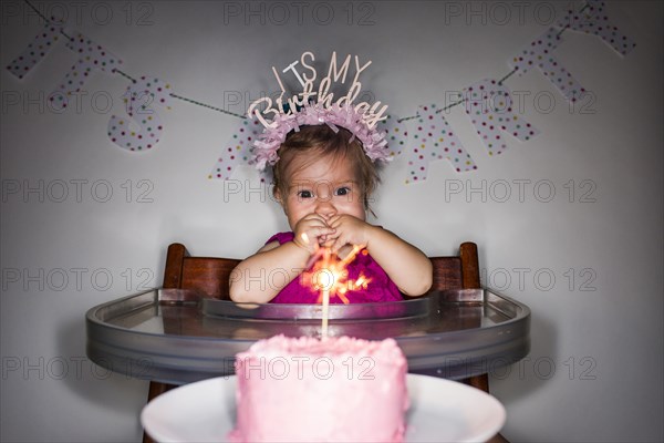 Caucasian baby girl admiring birthday cupcake