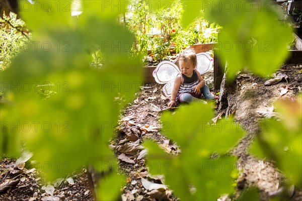 Caucasian baby girl wearing fairy wings in garden