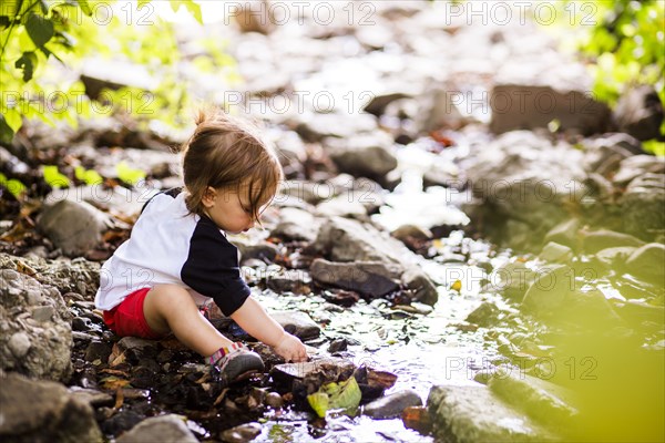 Caucasian baby girl playing in creek