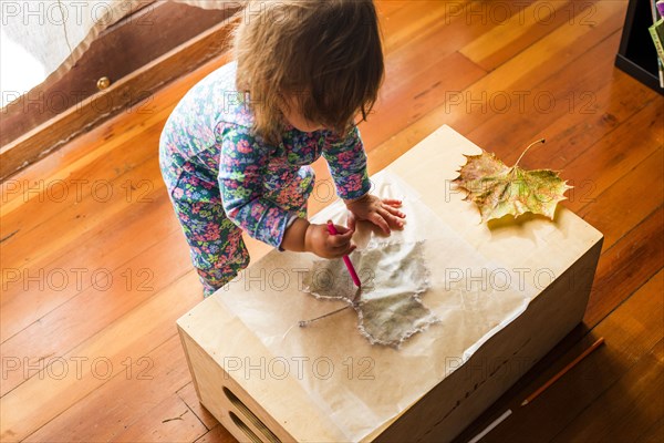 Caucasian baby girl drawing on leaf