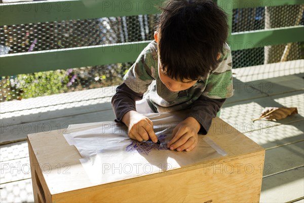 Mixed race boy drawing outdoors