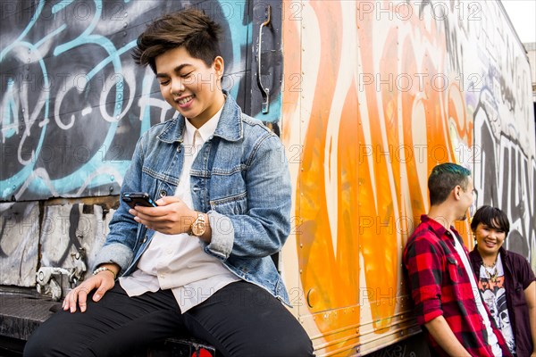 Woman using cell phone at graffiti truck