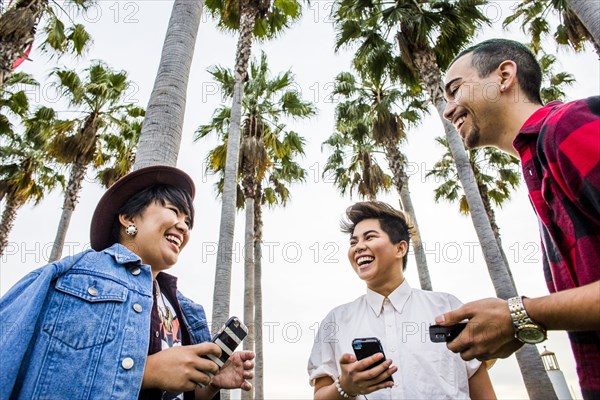 Low angle view of friends using cell phones outdoors