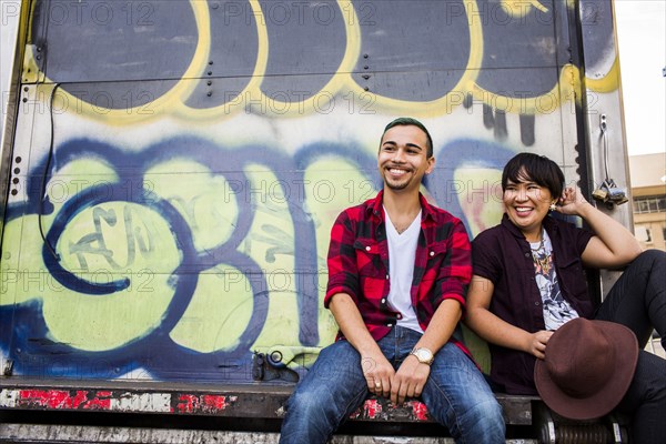 Couple sitting on graffiti truck