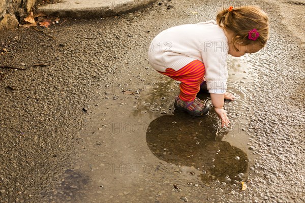 Caucasian baby girl playing in puddle