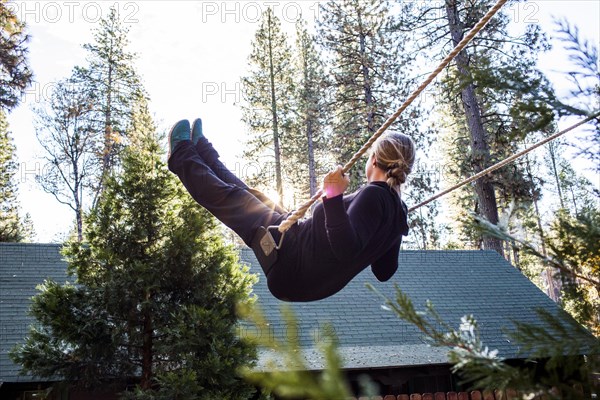 Caucasian woman playing on swing