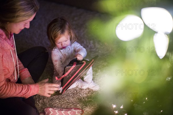 Caucasian mother and daughter opening Christmas gift