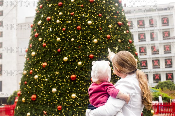 Caucasian mother and daughter admiring Christmas tree