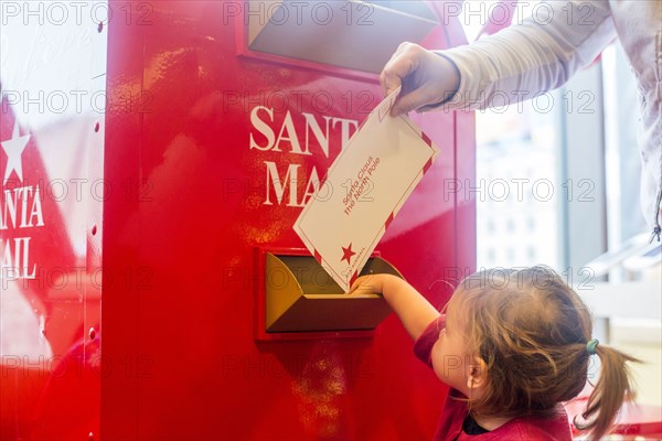 Caucasian mother and daughter mailing letter to Santa