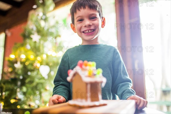 Mixed race boy smiling with gingerbread house