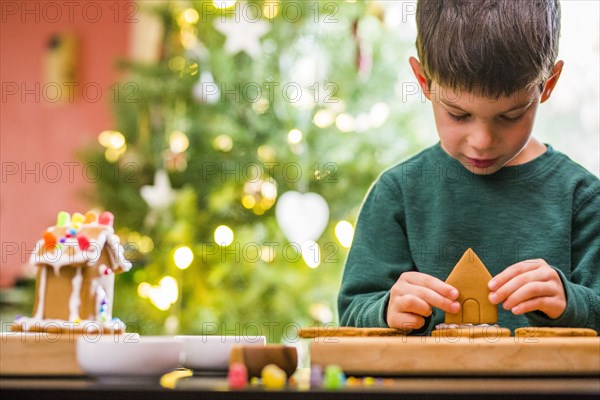 Mixed race boy building gingerbread house