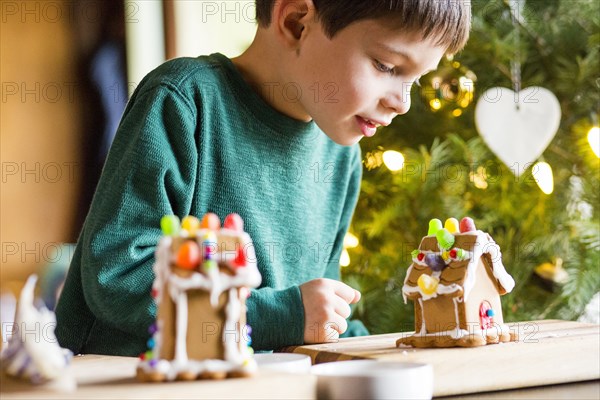 Mixed race boy building gingerbread house