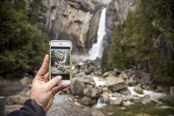 Man photographing waterfall in Yosemite National Park