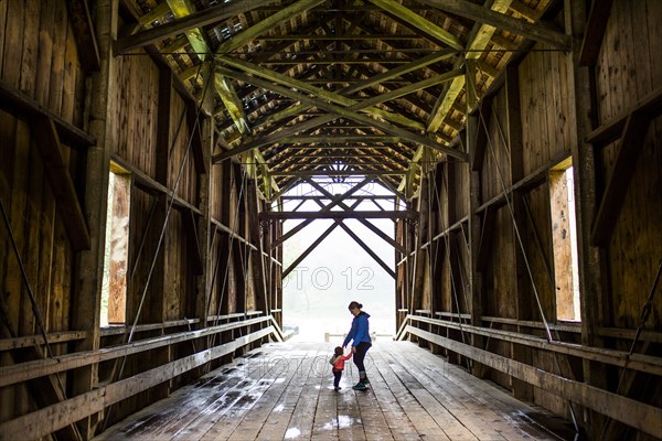 Caucasian mother and baby daughter on covered bridge