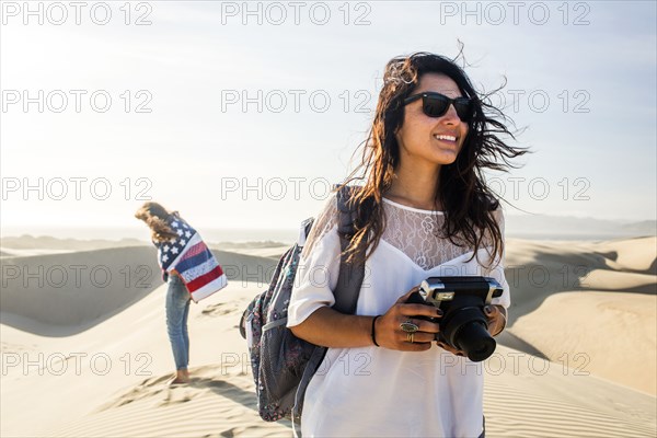 Mixed race woman photographing sand dunes