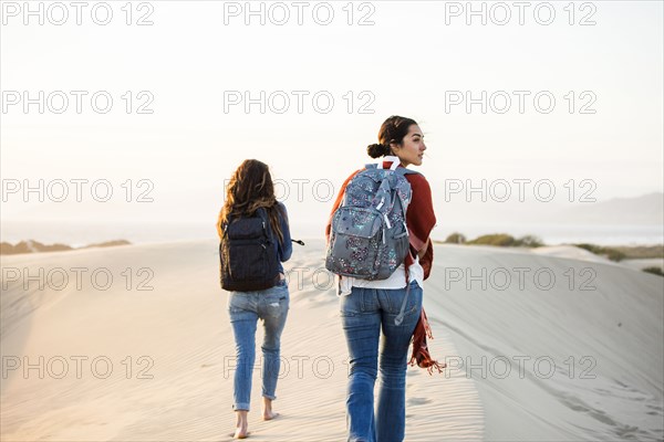 Mixed race women walking on sand dunes