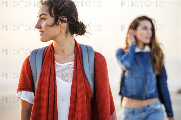 Mixed race women walking on beach