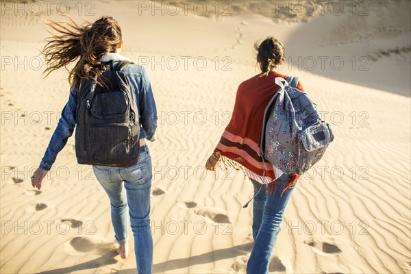 Mixed race women walking on sand dunes