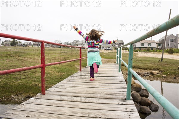 Carefree Caucasian girl running on wooden footbridge