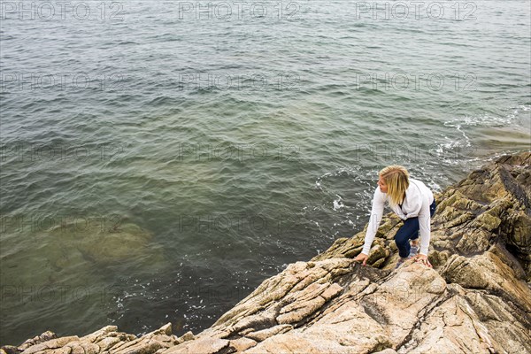 Caucasian woman climbing on rocks at ocean