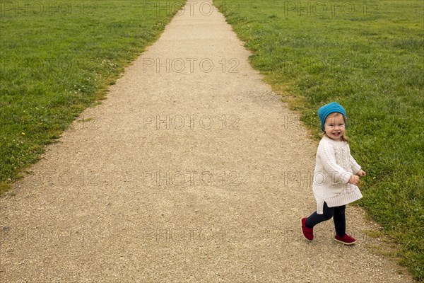 Smiling Caucasian baby girl walking on path