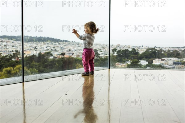 Curious Caucasian girl leaning on window admiring cityscape