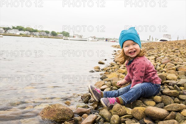 Smiling Caucasian girl sitting on rocks at river