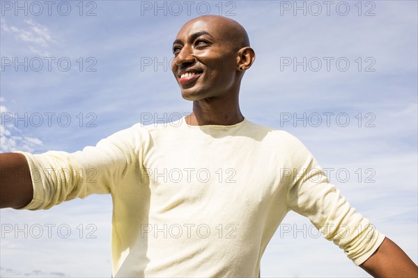 Smiling gay Black man under cloudy sky