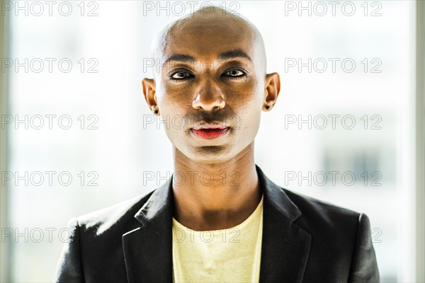 Serious gay Black man posing near window