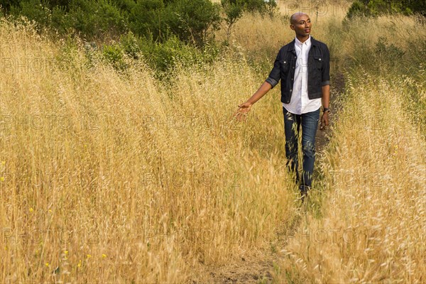 Pensive gay Black man walking in tall grass